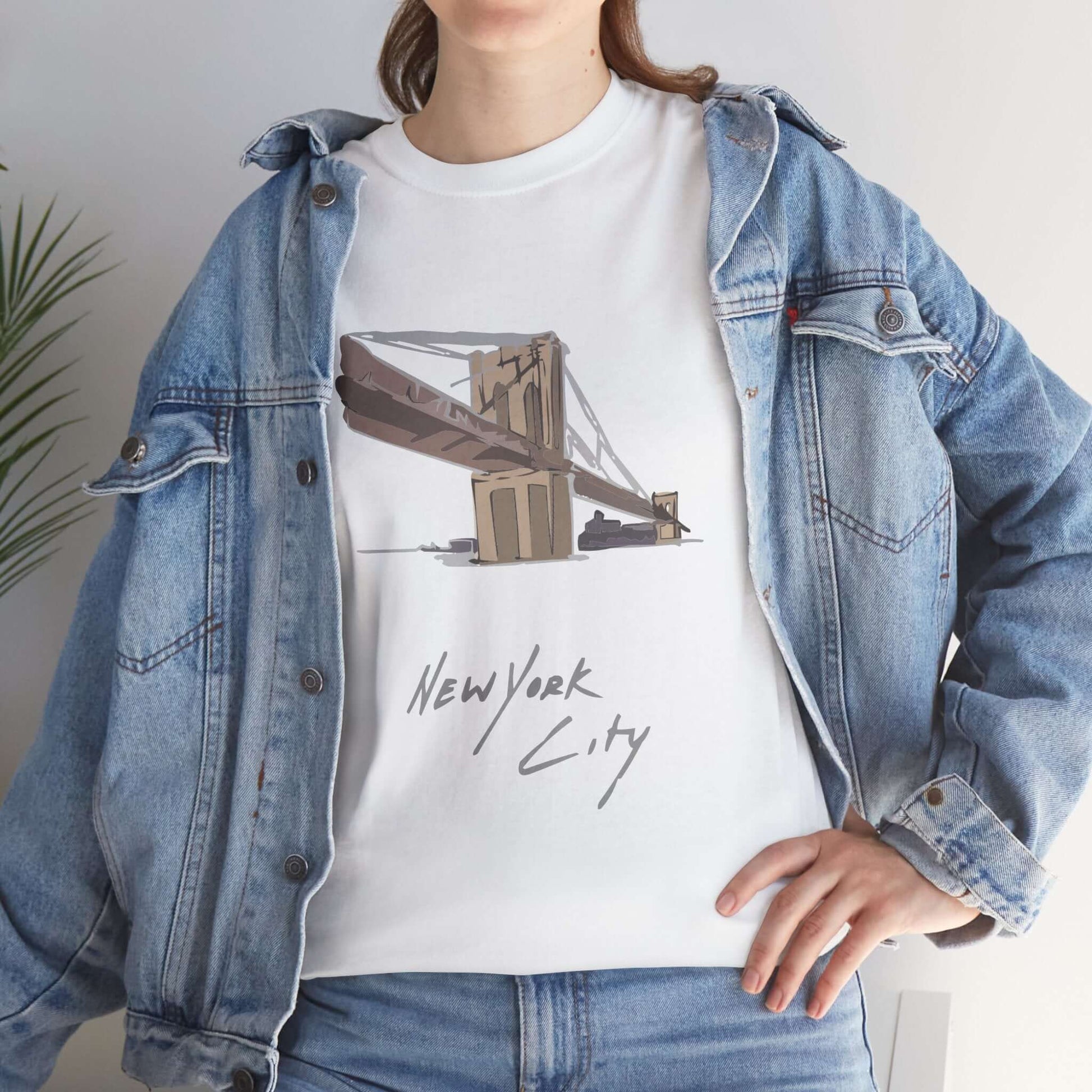 Person wearing Unisex New York City T-Shirt with bridge design and denim jacket, showcasing urban style.